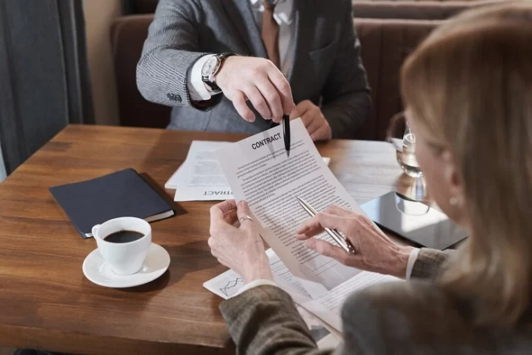 Two professionals reviewing and discussing a business contract at a table.