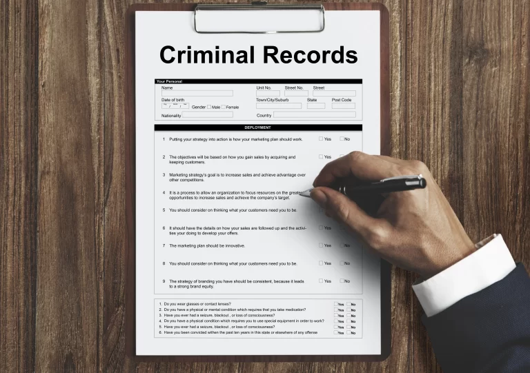 Person writing on a criminal record document, illustrating the benefits of expungement in Florida.