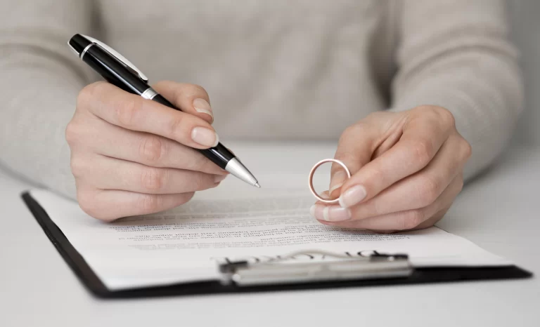Woman holding a wedding ring and signing a prenup agreement on a clipboard.