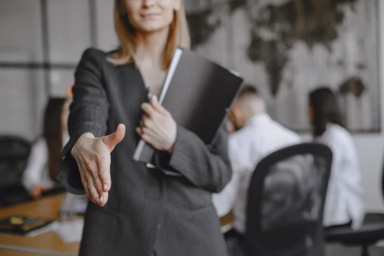Woman holding a job contract and offering a handshake, representing a non-compete agreement under Florida’s CHOICE Act.