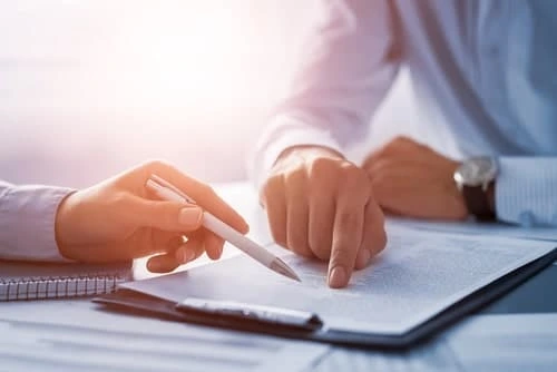 Two people reviewing and pointing at a contract document during a business discussion.